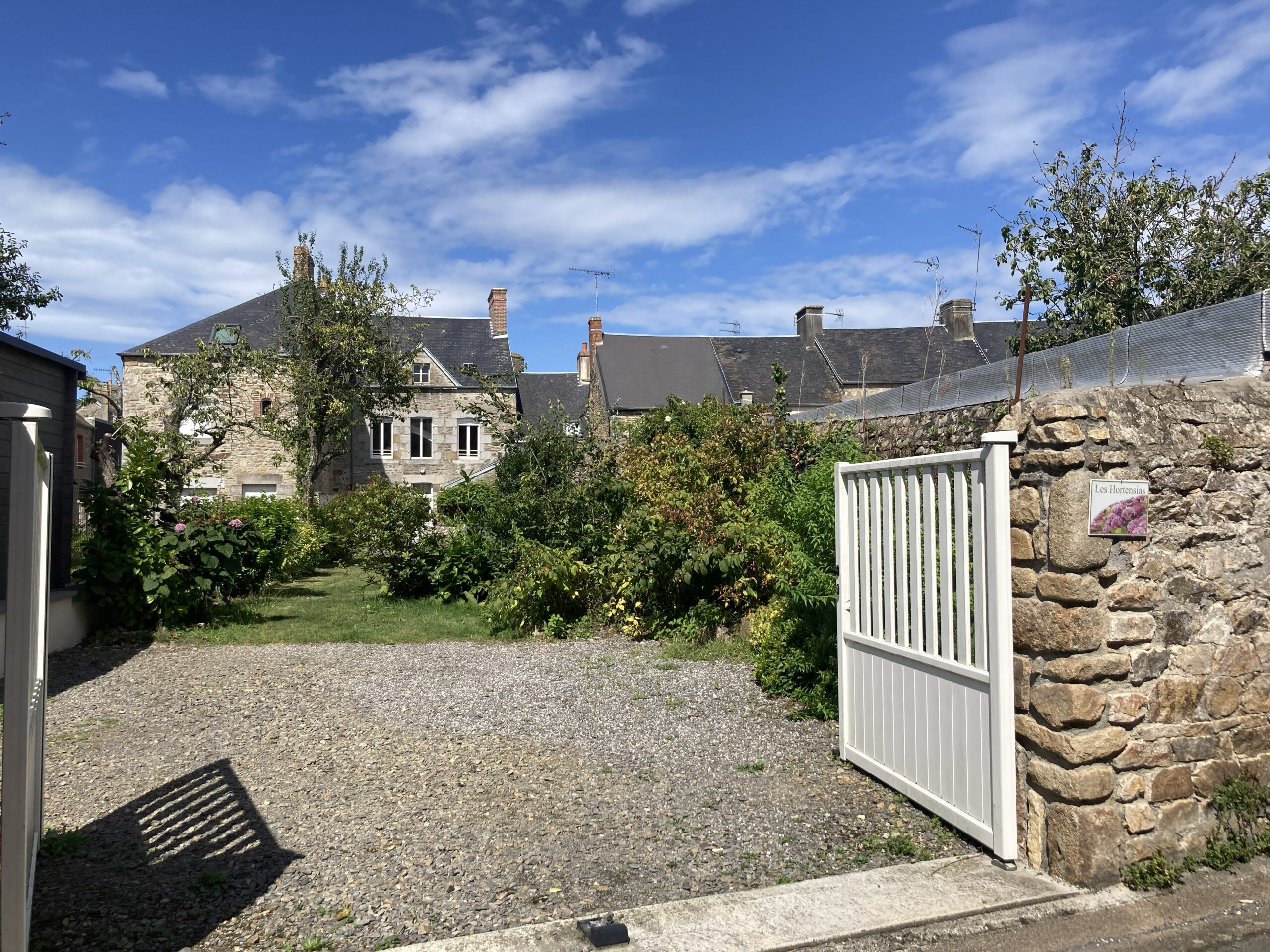Parking, jardin et maison au fond